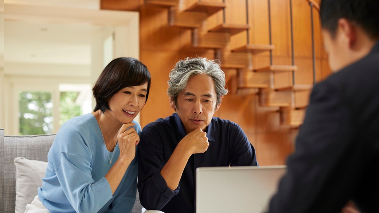A couple at home reviewing plans on a laptop with an advisor